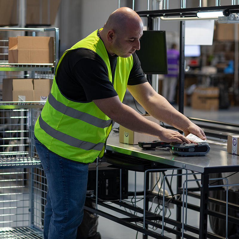 Man in a warehouse setting using a device on a table