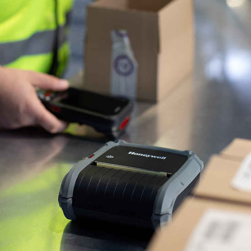 Person using a Honeywell barcode scanner in a warehouse setting