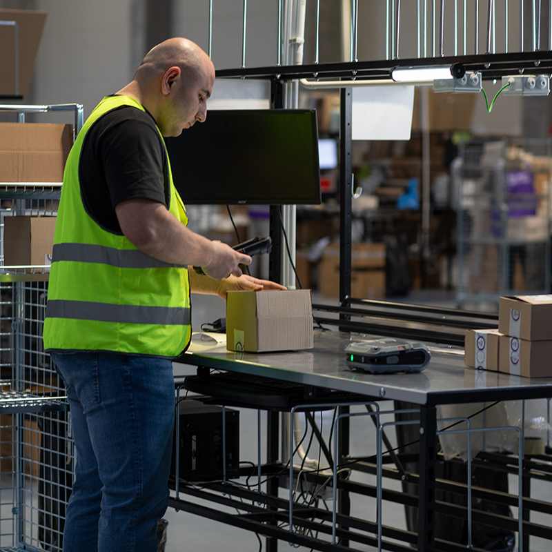 Person in a warehouse setting packaging items at a counter.